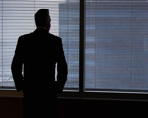 Person standing near a large office window looking outside